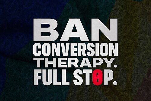 Banner with white text overlaid on a dark faded LGBT flag reading Ban Conversion Therapy Full Stop