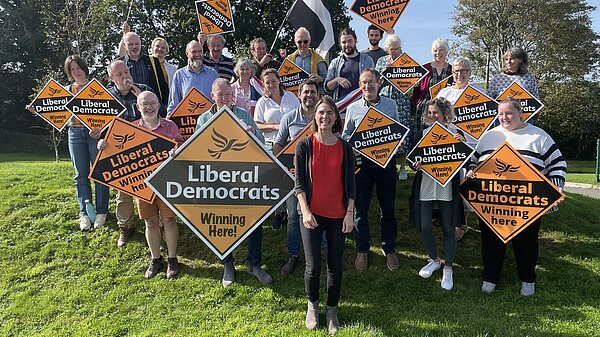 Ruth Gripper stands in front of group of people with Liberal Democrat signs 